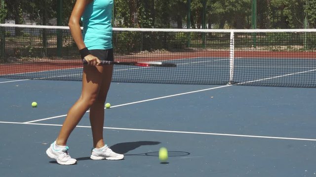 Sportsman beating ball by tennis racket. She wearing white sneakers. Girl is on a tennis court, ready te play