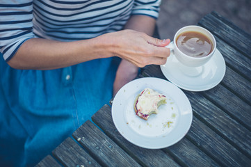 Woman drinking tea and eating scone