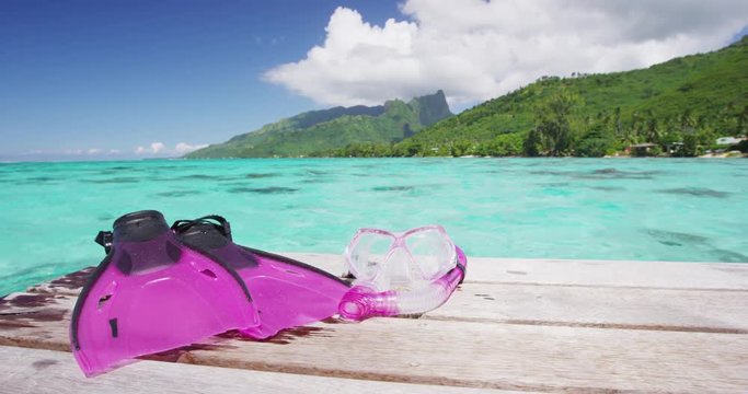 Snorkel mask and pink fins on overwater villa for swimming in coral reefs getaway, south pacific ocean. Pink female sport gear lying on deck in tropical destination Tahiti, French Polynesia.