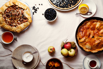 Traditional autumn pies arranged on white linen fabric. Chanterelle mushrooms, blueberry and sweet apple fillings. Top view, copy space.