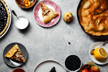 Traditional autumn pies on gray rustic concrete background. Chanterelle mushrooms, blueberry and sweet apple fillings. Tea time during the fall concept. Composition with copy space