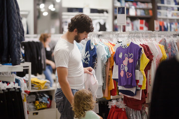 Attractive young father choosing baby clothes