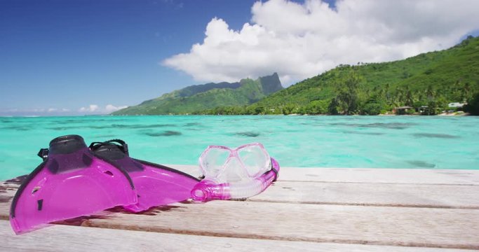 Snorkel mask and fins on overwater villa for swimming in coral reefs getaway, south pacific ocean. Pink female sport gear lying on deck in tropical destination Tahiti, French Polynesia.
