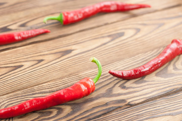 Four wholes red fresh ripe chili pepper on old brown wooden rustic planks