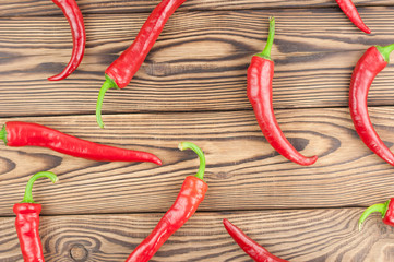 Scattered wholes red fresh ripe chili pepper on old brown wooden rustic planks