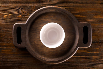 Obraz premium Mockup of empty white plate at wodden round tray at table background. Top view