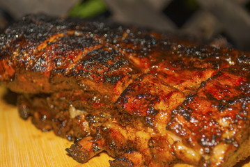 pork ribs marinated grilled on hot burning charcoal barbecue presented on wooden board close-up