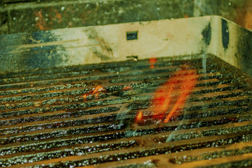 barbecue grid full of oil from marinated meat catching fire