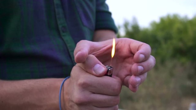 close up of person's hand light the fire on lighter. the bright lighter flame in slow motion