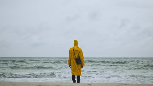 Person standing still waves at the shore from behind slow motion
