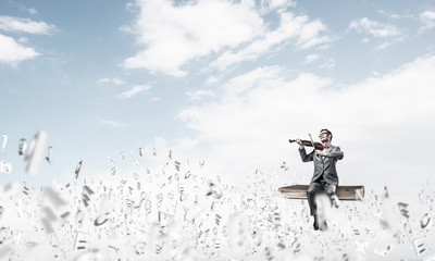 Handsome violinist play his melody and symbols fly around in air