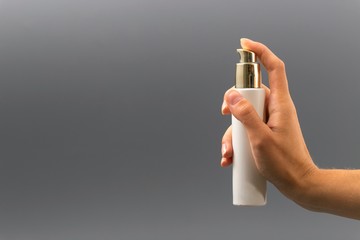 mini bottle sprayer on gray background in hand