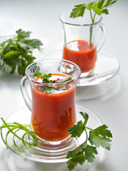 Tomato juice in glass mugs on glass plates