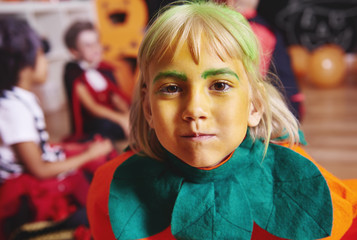 Cute girl in pumpkin costume staring