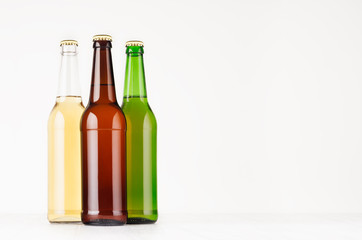 Set brown, green, transparent longneck beer bottles 500ml, mock up. Template for advertising, design, branding identity on white wood table.