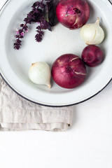 onions red and white, garlic and basil in a plate on a close-up table.