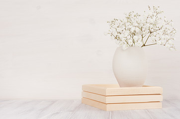Soft home decor of white small flowers in ceramic vase on white wood background. Interior.