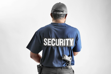 Fototapeta na wymiar Male security guard on light background