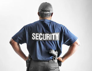 Fototapeta na wymiar Male security guard on light background