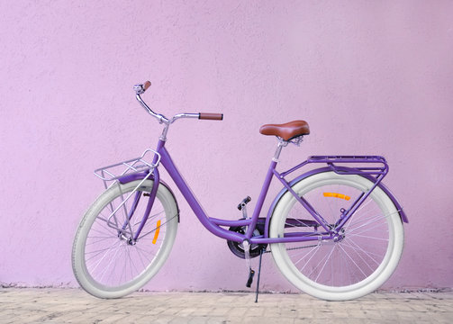Modern beautiful bicycle standing on color wall background