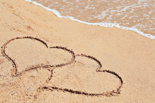 Drawing of hearts on sand. Beach wedding concept