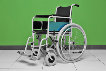 Wheelchair against color wall in room. Elderly care concept