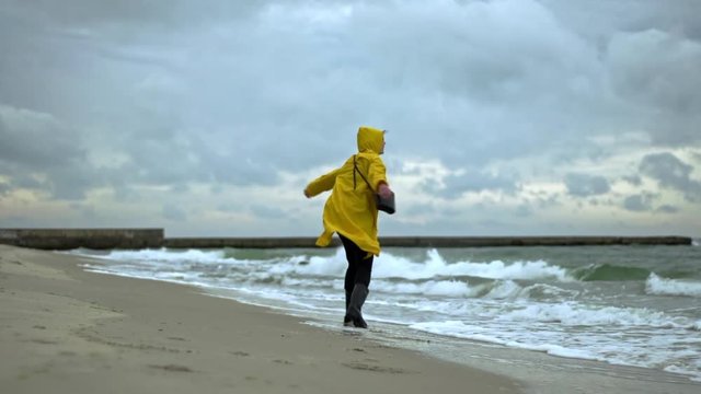 Young man happily running on beach spinning slow motion