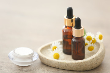 Cosmetics with chamomile extract on light background