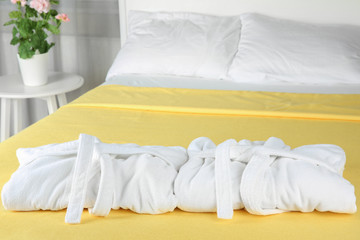 Fototapeta na wymiar Folded bathrobes on bed in room