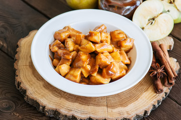 Aplle pie filling in a white plate on a wooden background. Traditional American baking