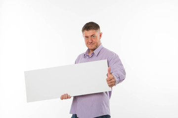 Young confident man portrait of a confident businessman showing presentation, pointing paper placard gray background. Ideal for banners, registration forms, presentation, landings, presenting concept.