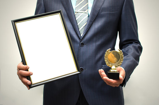 Top manager award mockup. Best office employee award. Business man holding empty blank photo frame (gratitude letter) in one hand and gold medal in another one. Gratitude concept. Grateful letter.
