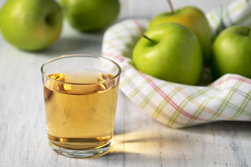 The juice of green apples in a glass on a wooden table. Soft focus.