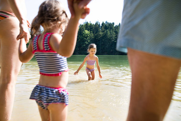 Little girls with lake. Sunny summer.