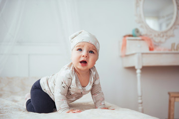 Newborn baby dressed in a suit on a soft bed in the studio.