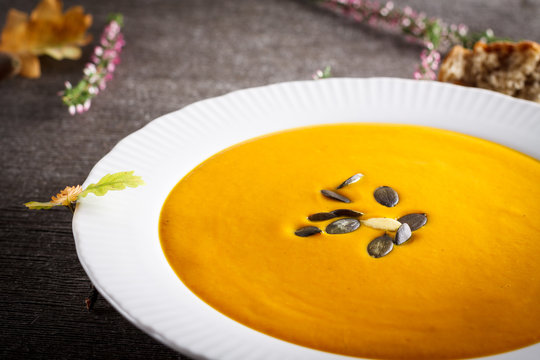 Autumn background scene of pumpkin soup with pumpkin seeds.