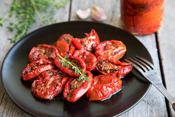 Bowl of sun dried tomatoes on wooden background. Sun dried tomatoes with olive oil and herbs