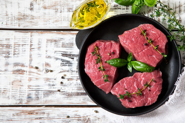 raw beef steak on a light wooden background with olive oil and spices