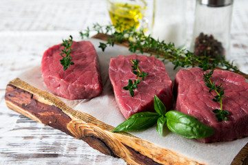 raw beef steak on a light wooden background with olive oil and spices