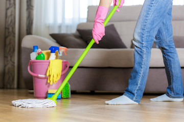 woman in protective gloves using a wet-mop while cleaning floor 