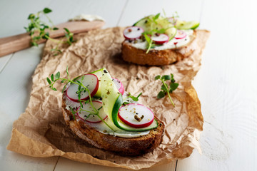 Sandwich with red radish, cucumber and fresh herbs and pepper.