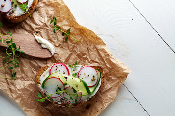 Sandwich with red radish, cucumber and fresh herbs and pepper.Top view with copy space.