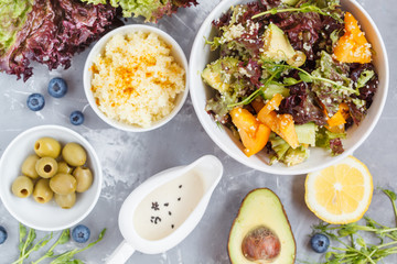 Bright colorful salad with couscous and vegetables, ingredients on the table, vegan lunch, top view.