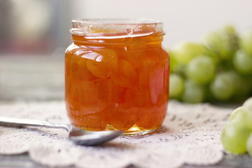 Preserves white grapes in glass jar, on wooden background - slatko -traditional serbian desert