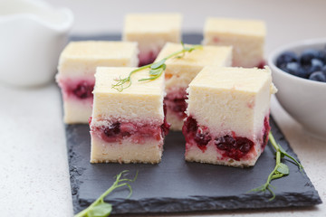 Mini cheesecakes with berries sliced squares on the slate.