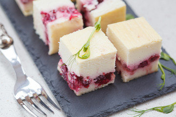Mini cheesecakes with berries sliced squares on the slate.