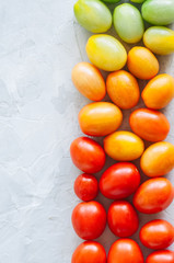 Bright colorful tomatoes cherry on a white stone background. Overhead view and copy space.
