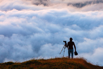 Photographer shooting natural phenomenon - the clouds that roam the mountains. Concept theme: nature, weather, tourism, extreme, healthy lifestyle, adventures. Unrecognizable persones.