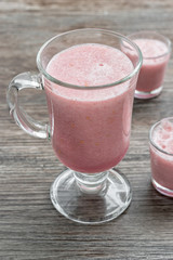 Pink drink berry smoothies. Smoothies in the large and small glasses on a wooden table .