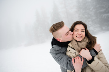 Obraz premium Handsome young man kissing her girlfriend from behind